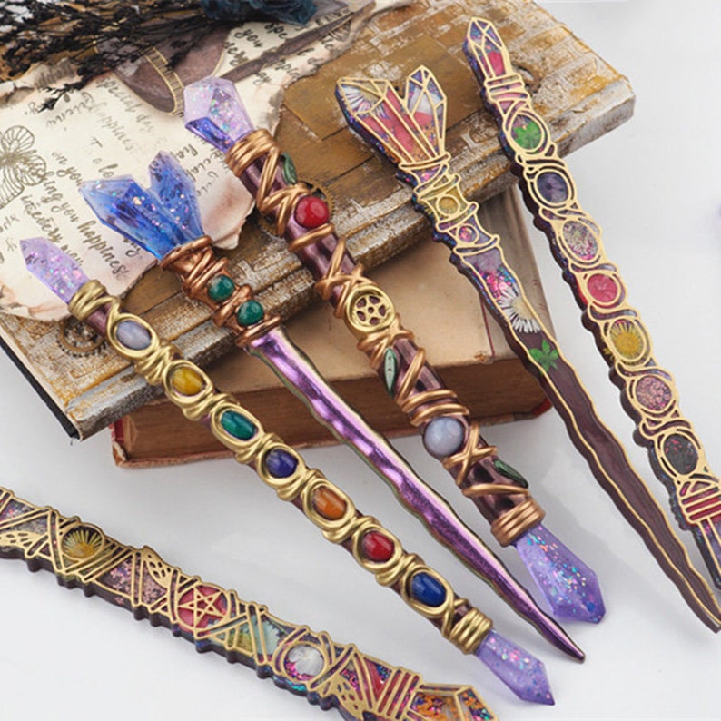 Puede incluir: Cinco varitas decorativas con detalles en morado, dorado y marr&oacute;n. Cada varita tiene una punta de cristal y est&aacute; adornada con gemas de colores y dise&ntilde;os intrincados.