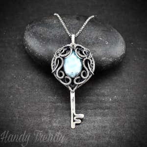 May include: A silver key pendant necklace with a blue and white gemstone set in a wire-wrapped design.