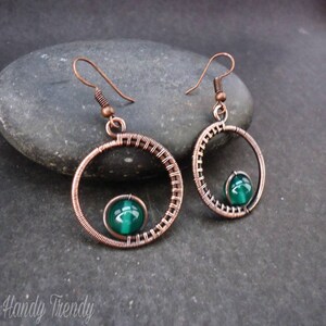 May include: Copper wire earrings with a green gemstone in the center of each circle.