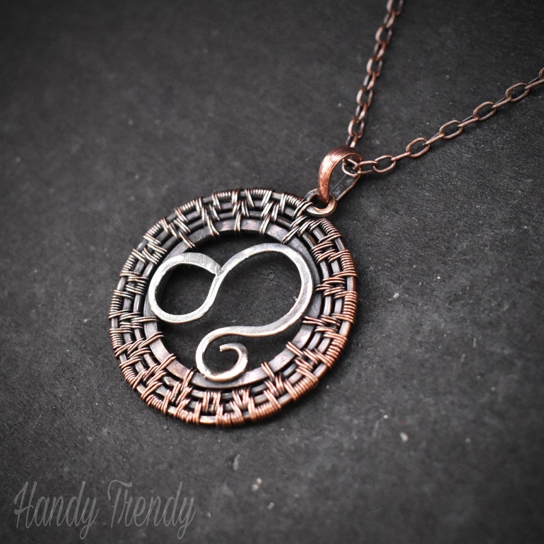 May include: A silver infinity symbol pendant with a copper wire woven circle around it. The pendant is attached to a copper chain.