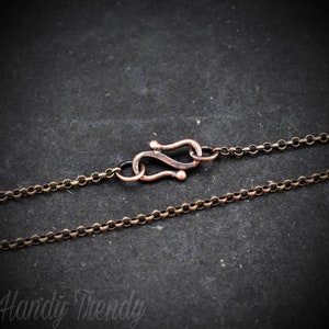 May include: A close-up of a copper-toned chain necklace with a lobster clasp closure. The chain is made of small, round links.