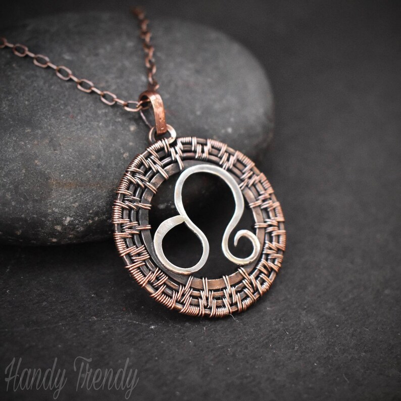 May include: A copper wire-wrapped pendant necklace featuring the Leo zodiac sign. The pendant is circular and has a silver Leo symbol inside.