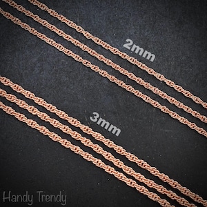 Puede incluir: Primer plano de dos collares de cadena de oro rosa, uno de 2 mm y otro de 3 mm de grosor, sobre un fondo oscuro. Las cadenas se muestran en diagonal, mostrando su intrincado diseño en forma de cuerda. El texto "2mm" y "3mm" es visible.