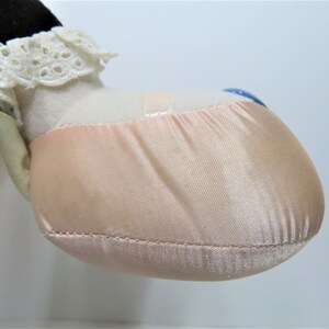 Puede incluir: Primer plano de una zapatilla de ballet de sat&eacute;n rosa con ribete de encaje blanco. La zapatilla forma parte de una mu&ntilde;eca o un animal de peluche.