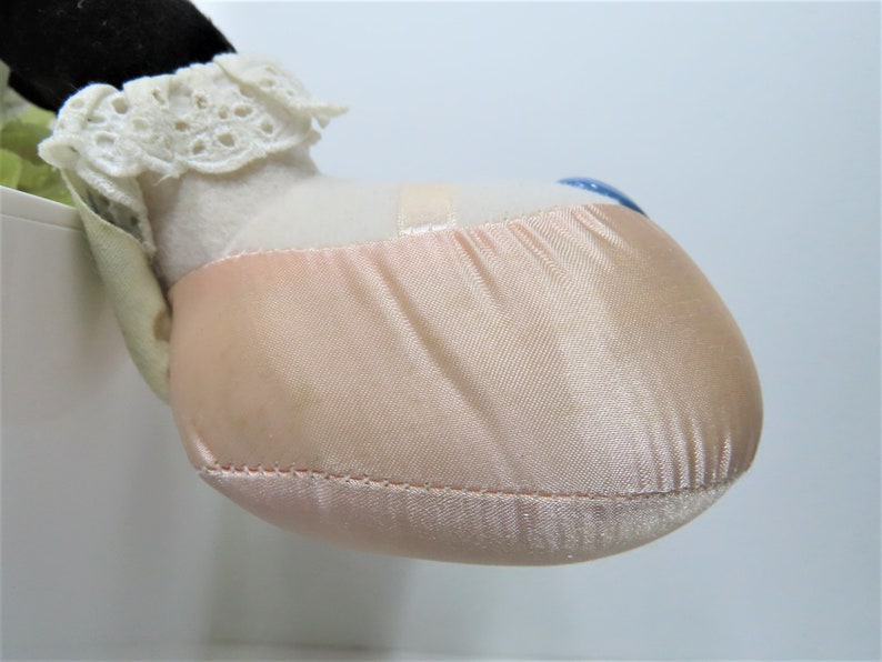 Puede incluir: Primer plano de una zapatilla de ballet de sat&eacute;n rosa con ribete de encaje blanco. La zapatilla forma parte de una mu&ntilde;eca o un animal de peluche.