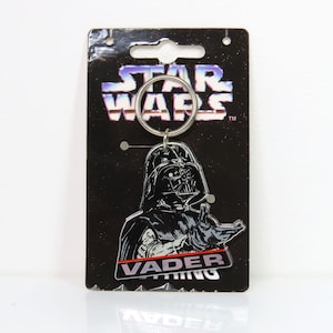 Un llavero de plástico vintage de Darth Vader de Star Wars de 1996 sobre cartón soporte.