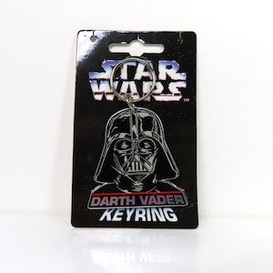 Un llavero de plástico vintage de Darth Vader de Star Wars de 1996 sobre cartón soporte.