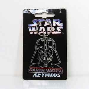 Un llavero de plástico vintage de Darth Vader de Star Wars de 1996 sobre cartón soporte.