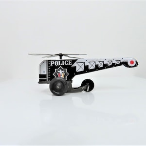 A vintage 1970s - 80s tin plate Police Helicopter toy.