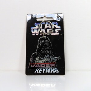 Un llavero de plástico vintage de Darth Vader de Star Wars de 1996 sobre cartón soporte.