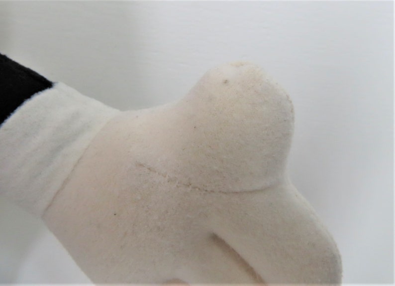 Puede incluir: Primer plano de un guante de felpa blanco con una costura que recorre la parte posterior de la mano.
