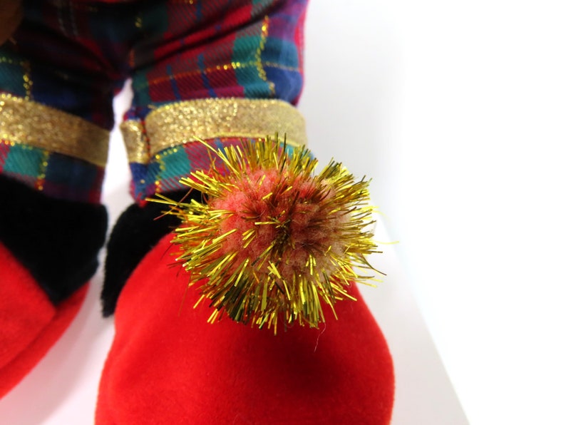 May include: Red and green plaid fabric with gold trim and a red fuzzy pom-pom with gold tinsel.