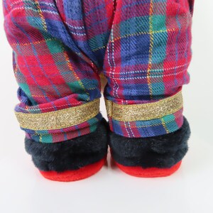 May include: Red and blue plaid pajama pants with gold glitter trim. The pants have black fur cuffs.