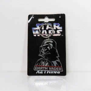 Un llavero de plástico vintage de Darth Vader de Star Wars de 1996 sobre cartón soporte.