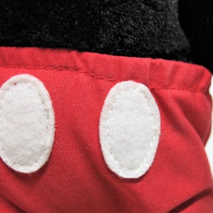 May include: Red shorts with white oval-shaped buttons. The shorts are made of a soft, plush fabric.
