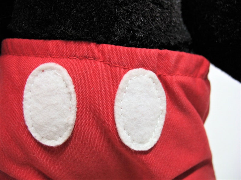 May include: Red shorts with white oval-shaped buttons. The shorts are made of a soft, plush fabric.