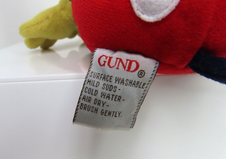 May include: A white tag with the word "GUND" in red lettering and the text "Surface Washable, Mild Suds, Cold Water, Air Dry, Brush Gently."