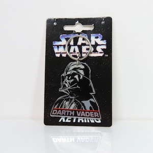 Un llavero de plástico vintage de Darth Vader de Star Wars de 1996 sobre cartón soporte.