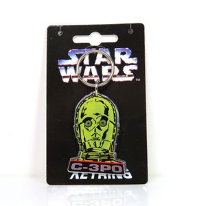 Un llavero de plástico vintage de C3PO de Star Wars de 1996 sobre cartón soporte.