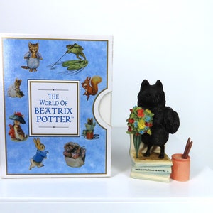 Puede incluir: Una figurita de gato negro sosteniendo un ramo de flores, de pie sobre una pila de libros. La figurita es parte de una colección llamada "The World of Beatrix Potter".