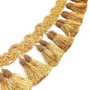 May include: Gold and orange tassel trim with a decorative woven design. The trim features a series of tassels with a gold sheen.