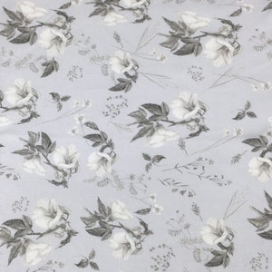 May include: A light blue fabric with a white floral pattern. The flowers are stylized and have a gray outline. The background is a light blue color.