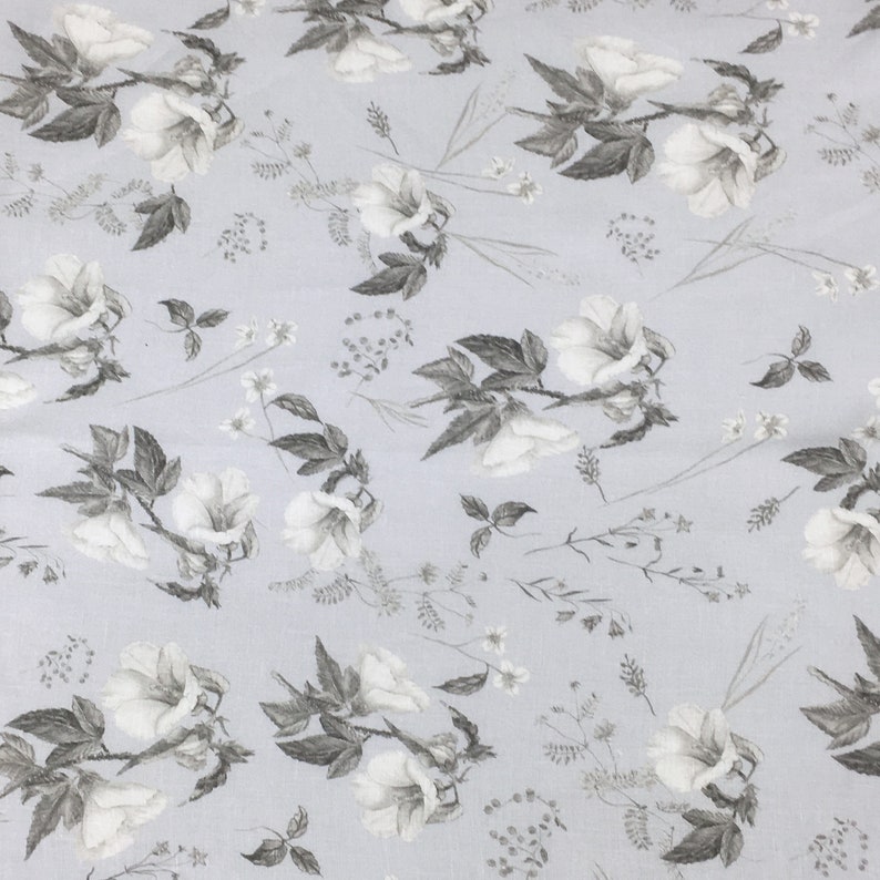 May include: A light blue fabric with a white floral pattern. The flowers are stylized and have a gray outline. The background is a light blue color.