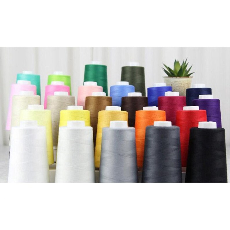May include: A collection of 24 spools of thread in various colors, including white, black, red, blue, green, yellow, orange, brown, and beige. The spools are arranged in rows and are all the same size.