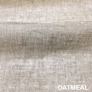 May include: Close-up of a textured, woven fabric in a light oatmeal color. The fabric has a subtle, uneven texture.