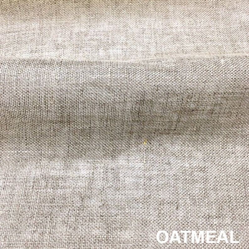 May include: Close-up of a textured, woven fabric in a light oatmeal color. The fabric has a subtle, uneven texture.