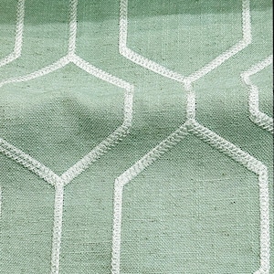 Puede incluir: Primer plano de una tela verde claro con un patrón geométrico blanco. La tela tiene una textura tejida y un brillo sutil.