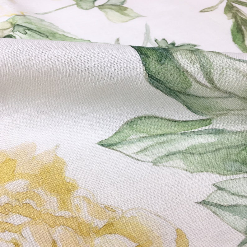 May include: White fabric with a watercolor floral pattern featuring yellow roses and green leaves.