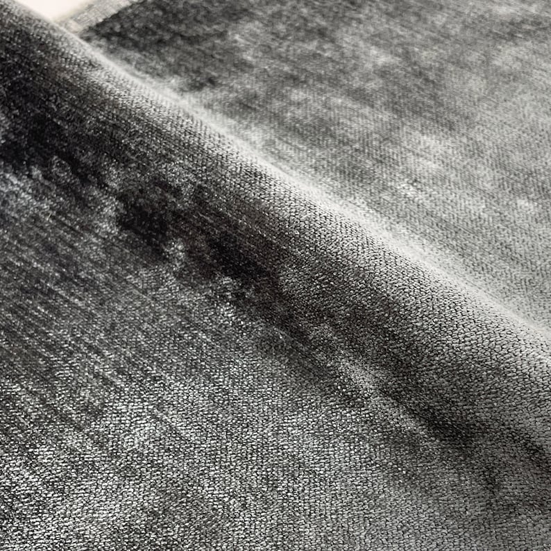 Puede incluir: Primer plano de una alfombra suave gris y negra con un brillo sutil. La alfombra tiene un aspecto texturizado y tejido.