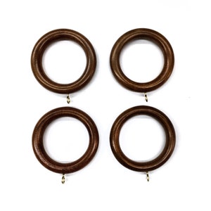 May include: Four brown wooden curtain rings with gold hooks. The rings are approximately 3 inches in diameter.