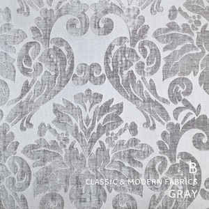 Puede incluir: Primer plano de una tela damasco plateada y blanca con un patr&oacute;n repetitivo de hojas y flores estilizadas. La tela es texturizada y tiene un brillo sutil. El texto "CLASSIC & MODERN FABRICS GRAY" est&aacute; impreso en la parte inferior de la imagen.