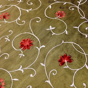 May include: Green fabric with a white embroidered floral pattern and red velvet flowers.