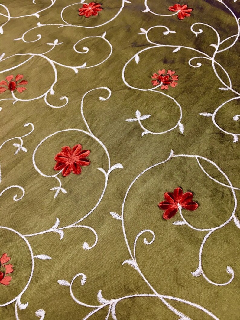 May include: Green fabric with a white embroidered floral pattern and red velvet flowers.