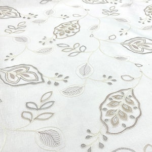 May include: White fabric with an embroidered pattern of gray and beige leaves and vines.