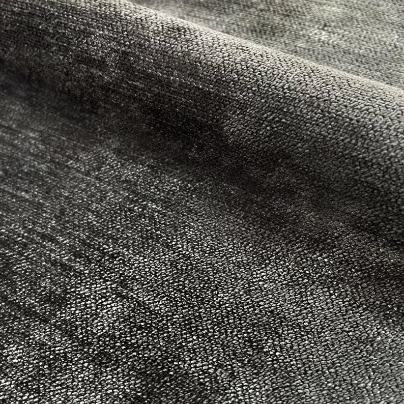 Puede incluir: Primer plano de una tela negra con una superficie texturizada. La tela tiene un brillo sutil y una sensaci&oacute;n ligeramente rugosa.