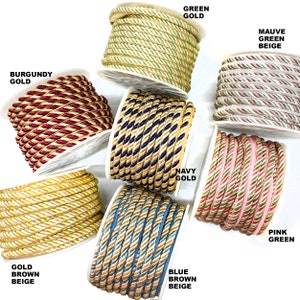 May include: Assortment of braided trim in various colors, including gold, green, navy, burgundy, pink, and blue. Each trim features a combination of two colors, creating a striped effect.