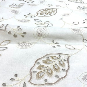 May include: White fabric with a delicate embroidered pattern of leaves in shades of brown and gray.