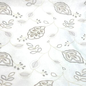 May include: White fabric with a delicate, embroidered pattern of gray leaves and vines. The design is reminiscent of a traditional floral motif.