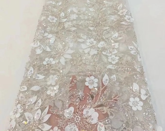 May include: White floral lace fabric with sequins and beads. The fabric has a delicate, intricate design with a floral pattern.