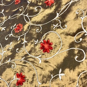 May include: Gold fabric with a white embroidered floral pattern and red velvet flowers.