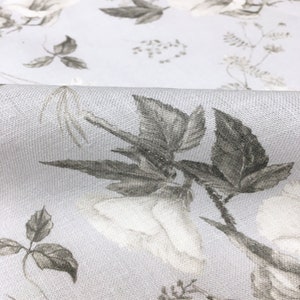 May include: A light gray fabric with a white floral pattern. The flowers are outlined in gray and have a subtle texture.