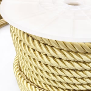 May include: A spool of thick, golden yellow rope trim. The rope is tightly wound and has a braided texture.