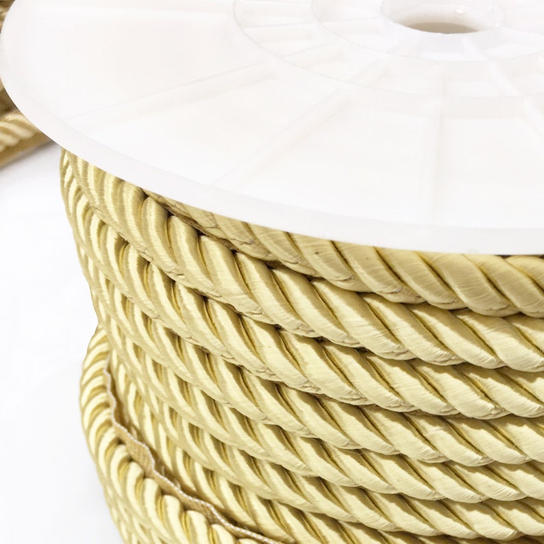 May include: A spool of thick, golden yellow rope trim. The rope is tightly wound and has a braided texture.