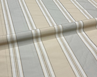 Puede incluir: Primer plano de una tela con rayas verticales. Las rayas alternan entre beige claro, gris claro y blanco. Finas líneas negras recorren los bordes de las rayas blancas. La tela está doblada, creando sombras suaves y textura.