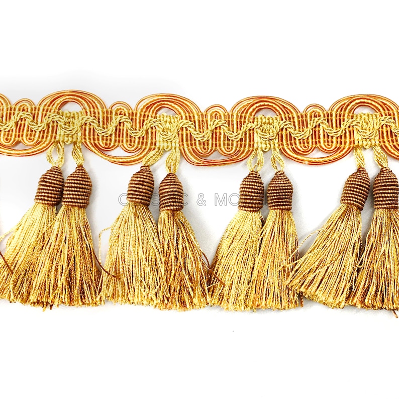 May include: Gold and brown tassel trim with a wavy design. The trim has a fringe of tassels with brown tops and gold strands.