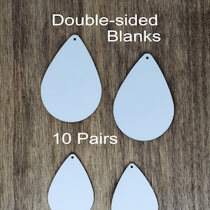 May include: Ten pairs of white, double-sided, teardrop-shaped earring blanks. The blanks have a hole at the top for attaching earring findings.  The blanks are arranged in two rows of four on a wooden surface.  Double-sided Blanks 10 Pairs